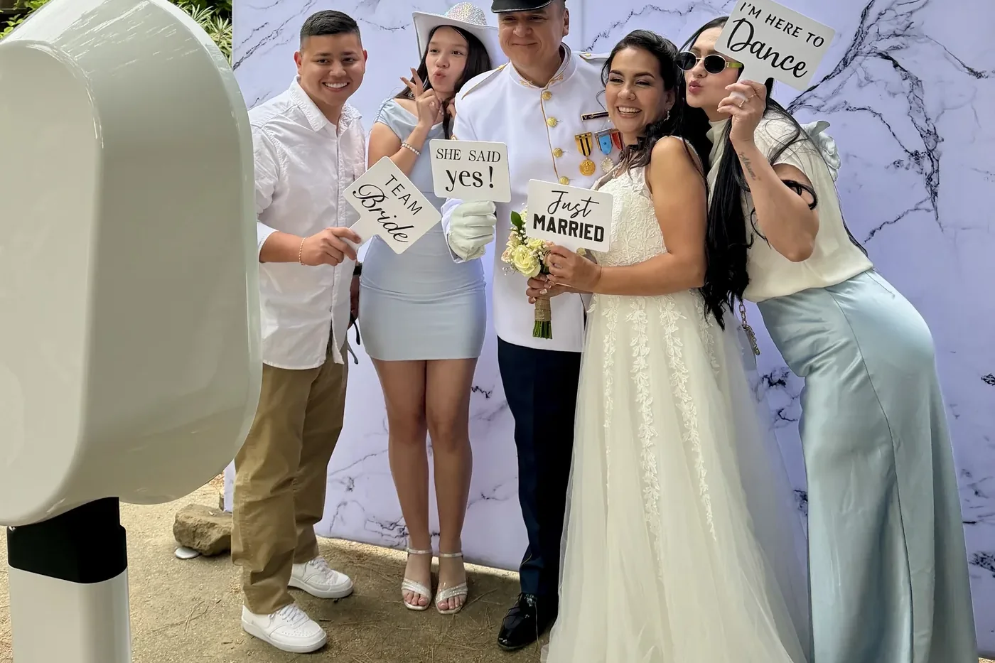 Wedding guests laughing with props in front of the Look at You photo booth