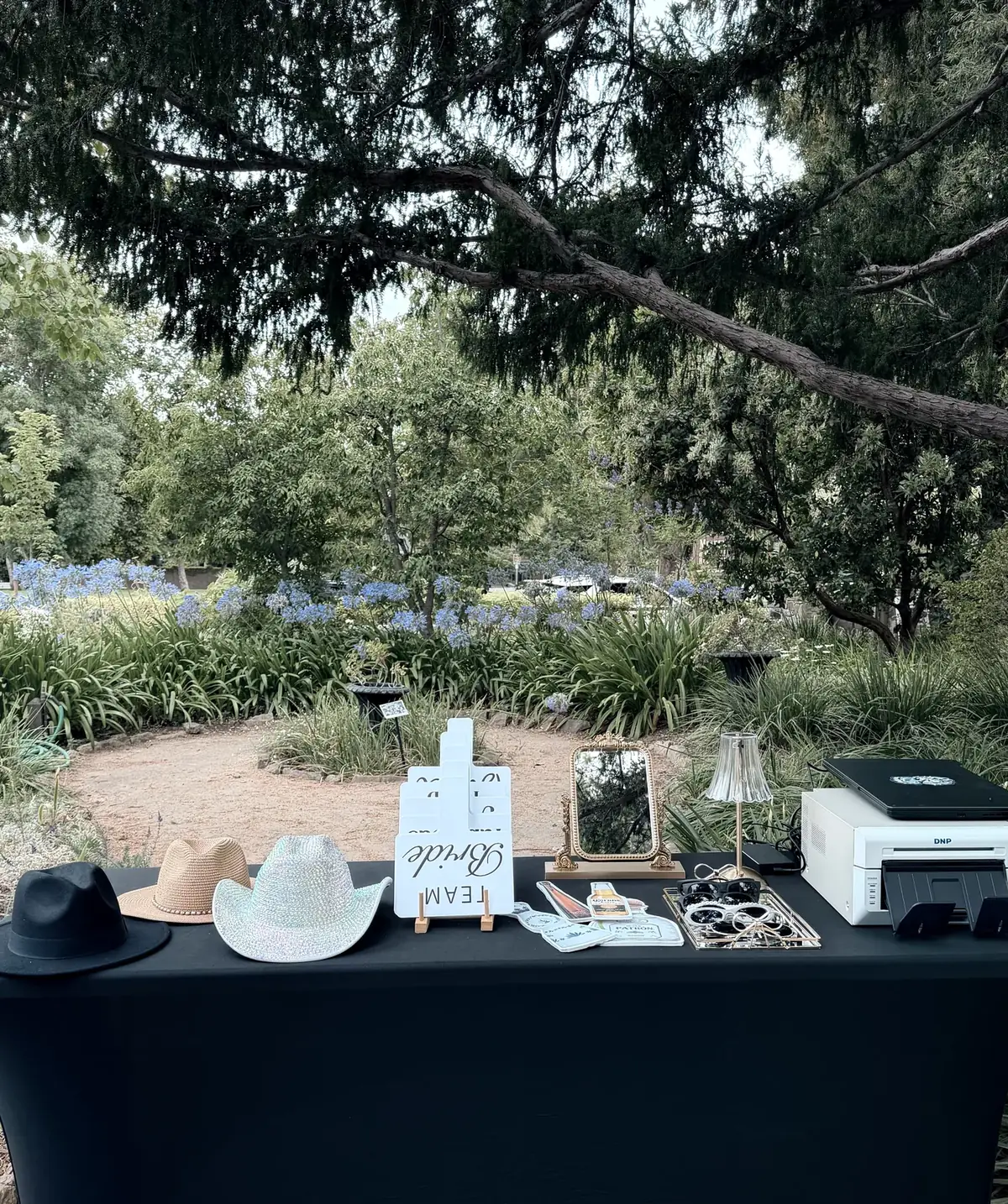 A full Look at You booth setup with props, mirror and instant printer at an outdoor wedding